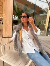 Chaleco de piel sintética en color gris, con diseño reversible. El interior presenta un forro de tela color mostaza con estampado floral bordado. Posee un corte holgado y sin mangas.