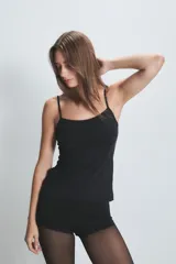 Musculosa de breteles finos en color beige, confeccionada en tejido suave y elástico, con diseño básico y ajuste al cuerpo.