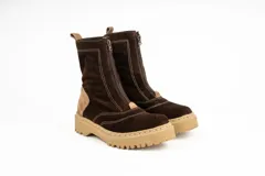 Bota tipo borcego de caña media, confeccionada en una combinación de cuero gamuzado negro y detalles en cuero color suela en la parte trasera y lengüeta. Presenta suela track de goma negra y costuras a la vista.