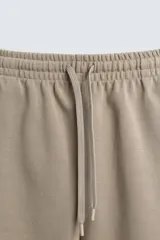 Bermuda de algodón color beige claro, corte relajado (relaxed fit), con cintura elástica ajustable mediante cordón y bolsillos laterales y trasero de plastrón.
