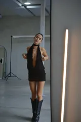 Vestido corto negro con diseño de cuello halter, escote profundo y espalda descubierta, confeccionado en tela liviana con caída.