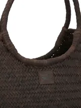 Cartera tipo tote de cuero trenzado en color marrón oscuro, con diseño artesanal de tejido en espiga y asas fijas trenzadas. Incluye un parche de cuero con el logo de la marca en el centro.