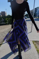 Falda midi de corte asimétrico con diseño cruzado en el delantero y aberturas. Presenta un estampado geométrico en tonos azul, negro y beige, con forro interior y cierre trasero con cremallera oculta.