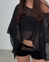 Poncho negro de mangas largas con detalle de transparencia en los hombros.