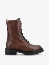 Borcego de caña media de cuero color marrón con efecto envejecido. Presenta sistema de cordones con ojales metálicos y suela track gruesa de goma negra.