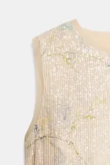 Top corto sin mangas, con cuello redondo, confeccionado en tejido de punto cubierto de lentejuelas con estampado floral en tonos azules y verdes sobre fondo beige. Cuenta con cierre en la espalda con abertura y botón.