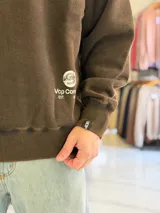 Buzo oversize de cuello redondo en color marrón con efecto gastado, con gran estampado en la espalda de estrellas y el texto VCP CNPT.