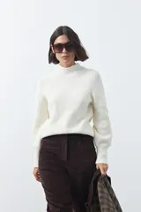 Polera de tejido de punto color blanco, con cuello alto y mangas largas con puños ajustados. Presenta una silueta relajada y diseño minimalista.