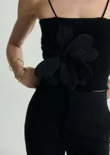 Top negro de tejido de punto fino con tirantes finos y detalle de maxi flor aplicada en el frente.