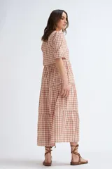 Vestido midi con estampado a cuadros color terracota y crudo, escote en V y mangas abullonadas cortas. Tiene corte imperio y falda escalonada.