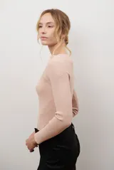 Buzo de morley color crema, con cuello bote y manga larga. Presenta un diseño de punto acanalado y un detalle de franja horizontal en el pecho.