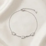 Pulsera de cadena fina de acero con tres dijes cuadrados engastados con circonias blancas.