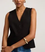 Chaleco negro de sastre, corte slim, sin mangas, con escote en V profundo y cierre frontal de cuatro botones. Presenta un bolsillo o falso bolsillo a la altura del pecho y está forrado.