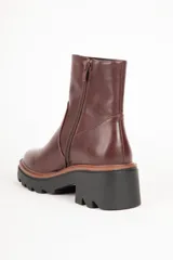 Bota corta de cuero sintético color negro, con punta redonda, cierre lateral y suela tipo tractor con plataforma de 6 cm.