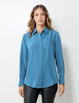 Camisa de satén color violeta, con cuello clásico, cierre frontal con botones, manga larga con puños anchos abotonados y bolsillo aplicado en el pecho.