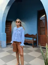 Bermuda de cuero sintético en color marrón, con diseño de corte recto, tiro medio y costuras verticales decorativas en el frente.