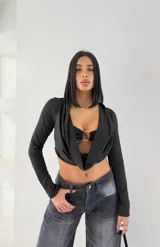 Top negro de mangas largas con escote drapeado y aro metálico en el centro.