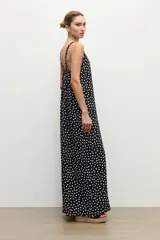 Mono largo negro con estampado de lunares blancos, escote en V y tirantes finos. Incluye un cinturón negro con hebilla doble redonda.