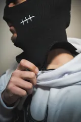 Hoodie blanco con pasamontañas negro incorporado, corte oversize, estampado en el pecho y mangas, y bolsillo tipo canguro.