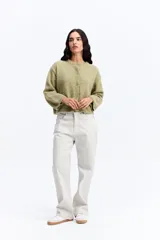 Saco de punto con textura tipo bouclé en color verde oliva, de calce relajado y diseño levemente cropped, con cierre frontal de botones.