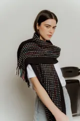 Bufanda larga tejida a crochet color negro con diseño de pequeños cuadrados blancos, rojos y azules. Termina en flecos cortos.