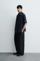 Camisa de corte relajado confeccionada en tejido fluido con textura acanalada. Presenta cuello solapa, manga corta y cierre frontal con botones.