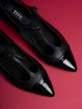 Chatitas negras de cuero sintético con punta charol y tira con hebilla.