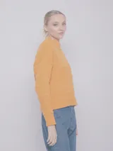 Sweater color crema de tejido de punto con cuello alto y mangas largas.