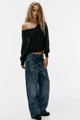 Jeans baggy de tiro medio con cinco bolsillos, trabillas para cinto y cierre frontal con cremallera y botón metálico. Cuenta con detalle de aplicación de brillos en toda la prenda.