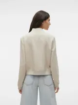 Campera tipo bomber de corte corto y diseño minimalista, confeccionada en tejido sarga color beige. Presenta cuello, puños y ruedo en tejido acanalado, cierre frontal con botones a presión y dos bolsillos delanteros con solapa.