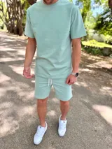 Conjunto deportivo para hombre compuesto por una remera de manga corta con cuello redondo y un short con cordón ajustable en la cintura, ambos en color verde menta.
