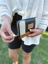 Billetera grande con cierre metálico, confeccionada en cuero. Presenta un diseño de bloques de color: negro texturado en el centro, beige texturado a los lados y cuero marrón liso en la parte inferior. Incluye un parche de cuero con la inscripción "chawie".