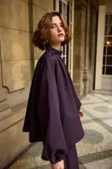 Campera de corte holgado y diseño minimalista en color marrón, con cuello alto, cierre frontal oculto y mangas largas con puños ajustados.