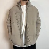 Campera puffer color beige, con cierre frontal completo y cuello alto. Diseño acolchado con costuras horizontales.