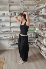 Pantalón negro de corte holgado y diseño abombacho, con cintura elástica fruncida, costuras decorativas y paneles en la parte inferior.