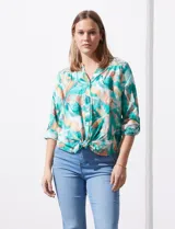 Blusa estampada de seda fría marca Figueroa & Flower. Tiene cuello a la base y escote en V, detalle de diferente estampa en hombros y espalda, apertura central con botones de nácar, mangas 3/4 regulables con presilla y botón, y terminación de ruedo con nudo.
