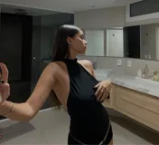 Catsuit negro con cuello alto, espalda descubierta y short ajustado. Incluye cinturón de cadena plateada con estrellas.