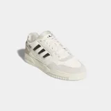 Championes Adidas Drop Step Low 2.0 de estilo urbano, con diseño inspirado en el baloncesto. Presentan una parte superior que combina ante y piel sintética en tonos crema y blanco, con las icónicas tres tiras laterales en color negro y el logo del trébol. Cuentan con una suela de goma esculpida y cierre de cordones.