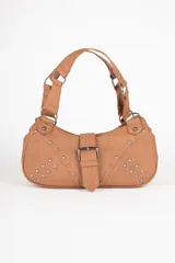 Cartera marrón de símil cuero con detalles de pespuntes y apliques de tachas metálicas. Cuenta con hebilla, dos asas fijas y un bolsillo adicional en su interior.