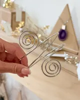 Brazalete rígido de metal plateado con diseño de doble espiral en los extremos, ajustable para el brazo.