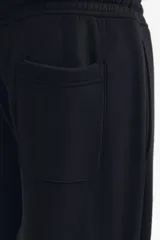 Pantalón deportivo de felpa de mezcla de algodón color negro, con cintura elástica ajustable mediante cordón, bolsillos en las costuras laterales y puños acanalados.