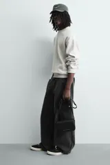 Bandolera negra con textura grabada, correa ajustable, monedero extraíble, compartimento principal con solapa imantada, bolsillo interno con cierre y bolsillo frontal con cierre.