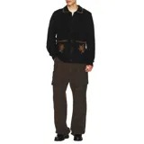 Buzo tipo cárdigan de punto color negro, con cierre frontal de botones, cuello tipo polo y dos bolsillos frontales. Presenta detalles de costura decorativa en color contrastante en el cuello y los bolsillos, además de un bordado floral en cada bolsillo.