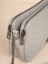 Bandolera negra con diseño acolchado en forma de zigzag, correa de cadena plateada y correa de cuero sintético ajustable.