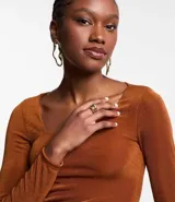 Vestido corto color marrón, de poliéster con elastano, con escote asimétrico, mangas largas y detalle fruncido lateral.