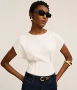 Blusa blanca de algodón con cuello redondo, mangas cortas estructuradas y diseño corsetado con pliegues en la cintura.