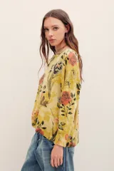 Sweater de punto color mostaza con estampado floral y de mariposas, cuello redondo y mangas largas.