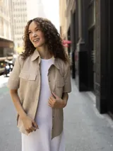 Camisa negra de cuero de cordero con corte recto, mangas cortas, cuello clásico, cierre frontal con botones a presión y dos bolsillos de parche en el pecho.