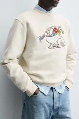 Sudadera de cuello redondo y manga larga con calce relajado. Presenta un bordado frontal de un conejo con flores y detalles en contraste, con terminaciones en rib en puños y ruedo.