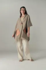 Chal de lana fina sin teñir con diseño de cuadros sutiles, cierre frontal con alamar y bolsillos de cuero metalizado. Presenta terminaciones con flecos en el ruedo y un calce estructurado en los hombros.